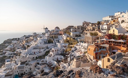 Cliff-side houses, villas and windmill in the village of Oia, Ia, as seen from the Kasteli Castle,