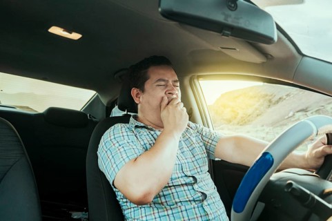 View of a sleepy driver in his car. Tired driver yawning in the car, concept of man yawning while