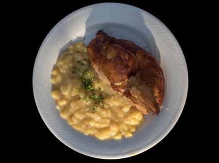 Half baked chicken with potato salad on a black background, Bavaria, Germany, Europe