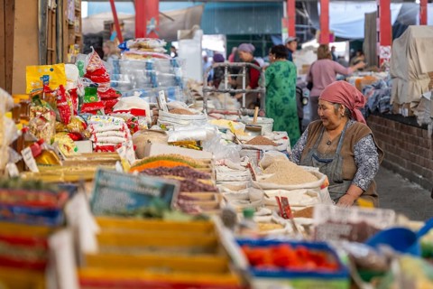 Traditional woman selling spices, flour and food, market stall at Osh Bazaar, Bishkek, Kyrgyzstan,