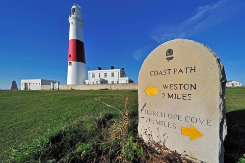 Portland Bill lighthouse and stone waymarker on the Isle of Portland along the Jurassic Coast,