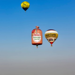 Three hot-air balloons travelling in the blue sky, advertising for Reinert Sommerwurst, BVB, Brian