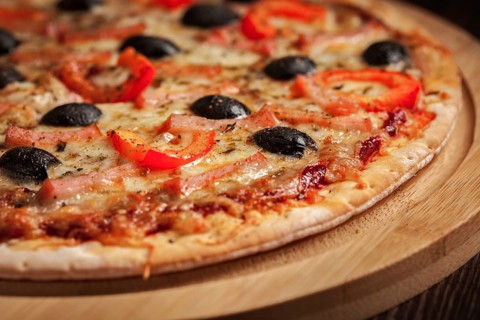 Ham pizza with (capsicum) and olives on wooden board on table close up