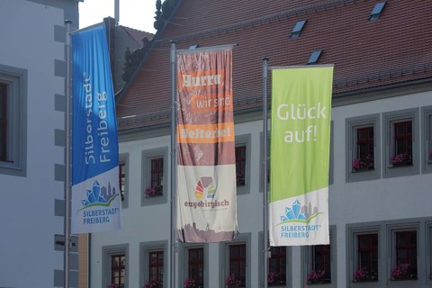 Three flags with inscription Silberstadt UNESCO at the town hall, symbol, mining, Obermarkt,