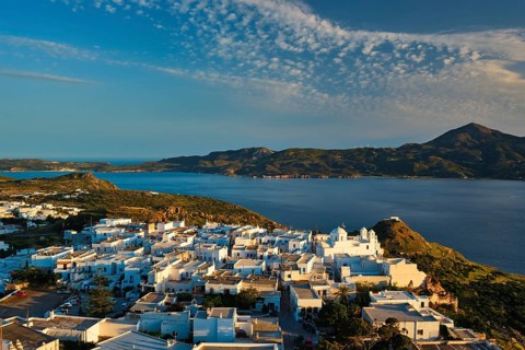 View of Plaka village on Milos island with traditional greek white houses on sunset. Plaka town,