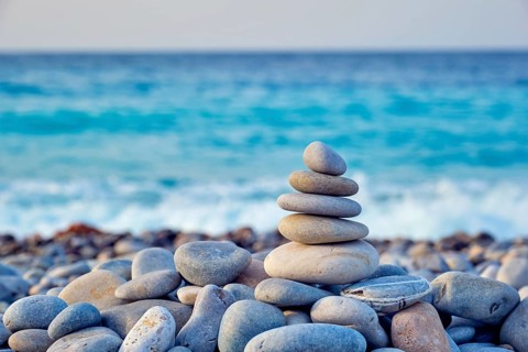 Zen meditation relaxation concept background, balanced stones stack close up on sea beach