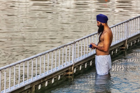 AMRITSAR, INDIA, AUGUST 26, 2011: Sikh man praying and bathing in holy tank around Harmandir Sahib