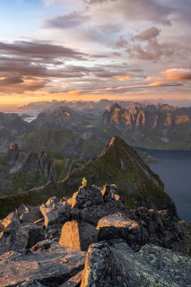 View over mountain peaks and sea, dramatic sunset, mountaineers at Hermannsdalstinden, with fjord