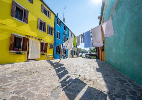 Clothesline between colourful houses, colourful house facades, alleys on the island of Burano,