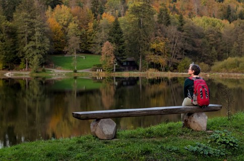 Older woman with backpack, Best Ager, sitting lonely on wooden bench, Ebnisee, Kaisersbach, autumn,