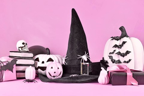 Pink Halloween decor with black and white pumpkins, witch hat, spell books, gifts and spiders