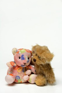 Two different teddy bears, leaning towards each other