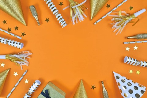Party objects like paper hats, confetti, golden champagne bottles and star confetti forming frame