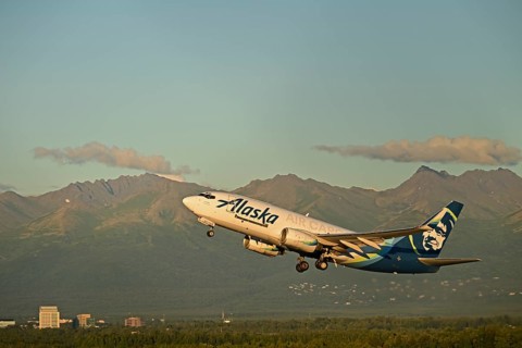 Against the backdrop of the Chugach Mountains and the houses of Anchorage, an Alaska Airlines cargo