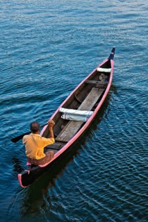 KERALA, INDIA, MAY 5, 2010: Indian man in small canoe boat in backwaters. Kerala backwaters are