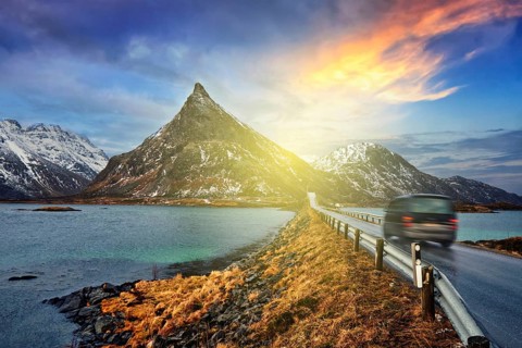 Car on road in Norwegian fjord on sunset. Lofoten islands, Norway. With motion blur