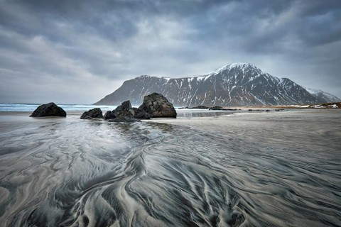 Rocky coast of fjord of Norwegian sea in winter with snow. Skagsanden beach, Lofoten islands,