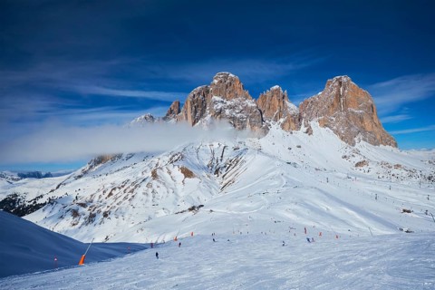 View of a ski resort piste with people skiing in Dolomites in Italy