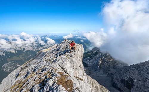 Mountaineer on a rocky narrow mountain path with mountain panorama, mountain tour to the summit of