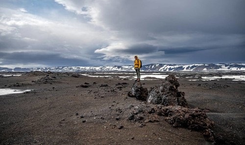 Hikers in snow-covered volcanic landscape with volcanic sand and petrified lava, crater of Askja