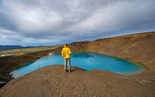 Tourist at volcanic crater with blue lake, volcanic lake, crater lake Viti at central volcano