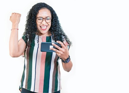 Excited young afro girl holding phone celebrating something. Happy afro woman holding smartphone