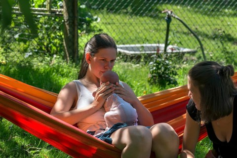 Young mother with baby in a hammock in the garden, sister on the right, Mecklenburg-Vorpommern,