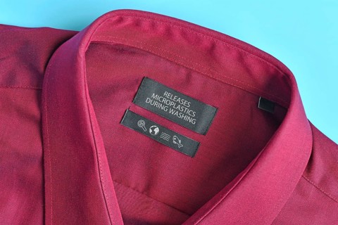 Shirt with label saying 'Releases microplastics during washing'. Concept for synthetic clothing