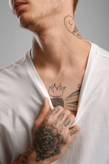 Cropped image of young tattooed man pulling his t-shirt