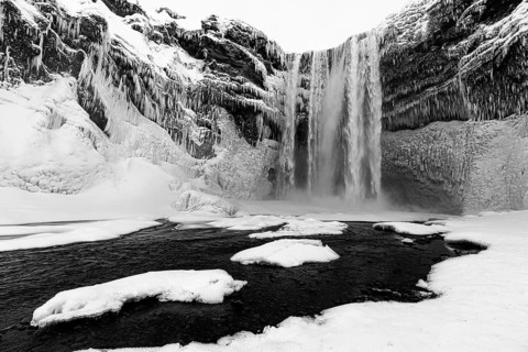 Skogafoss waterfall with icy and snowy rock face, black and white photo, Sudurland, Iceland, Europe
