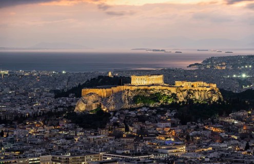 View over the sea of houses of Athens, illuminated Parthenon temple on the Acropolis, from Mount