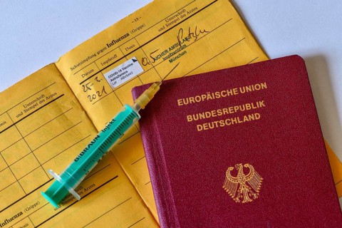 Passport, syringe and vaccination certificate with entry for vaccination with AstraZeneca against