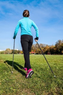 Nordic walking adventure and exercising concept, woman hiking withnordic walking poles in park