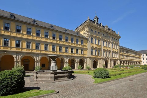 Inner courtyard and fountain with baroque princely building with arcade and gardens of the
