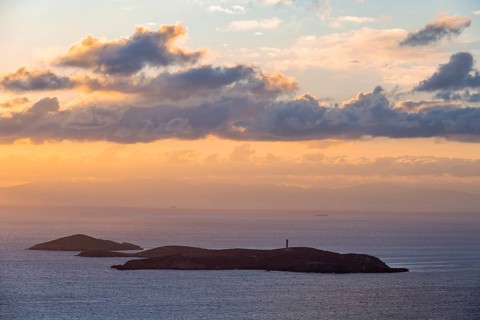 Nisos Gaidaros island with lighthouse in the sea at sunrise with dramatic clouds, Ermoupoli, Syros,