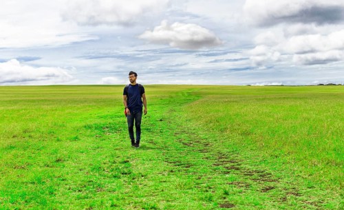 Traveler man walking in the beautiful countryside. Backpacker man walking in a countryside.