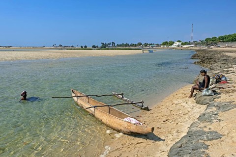 Single-outrigger canoe and two local Malagasy women on the beach at the coastal village Belo sur