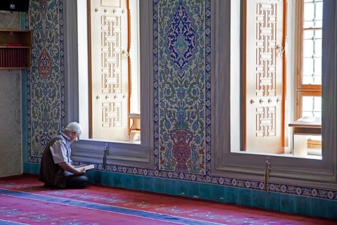 Turkish man reading the Koran in the Kocatepe Camii, largest mosque in Ankara, Turkey, Asia