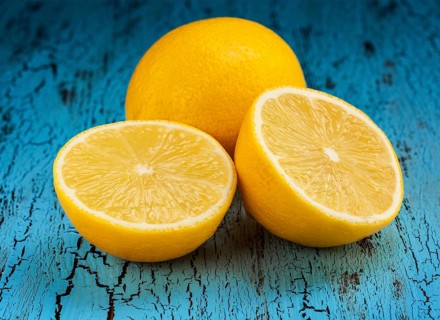 Lemon and cut half slice on blue wooden background