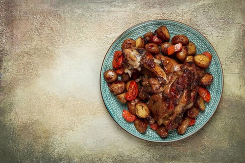 Pork knuckle baked with vegetables, new potatoes, on a plate, homemade, no people