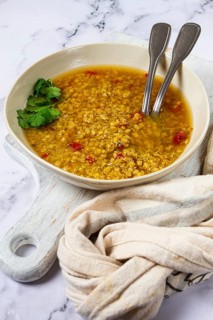 A bowl of lentil soup filled with warm, rich flavors, garnished with fresh herbs, accompanied by