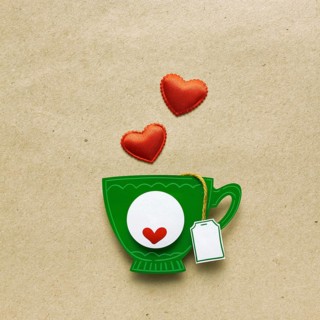 Creative valentines concept photo of a cup of tea with paper hearts on a brown background
