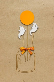 Creative Halloween concept photo of a bottle with ghosts made of paper on a brown background