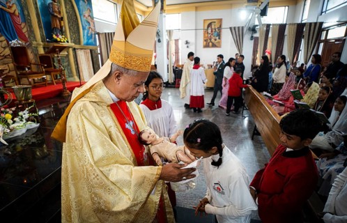 Archbishop John Moolachira holds an idol of baby Jesus Christ as devotees kiss the idol during a