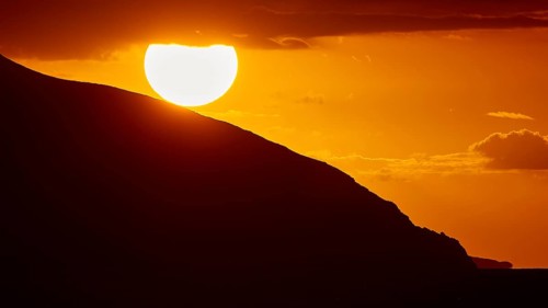 Sinking sun behind a mountain slope, intense orange light in the sky, sunset, Kassos, Karpathos,