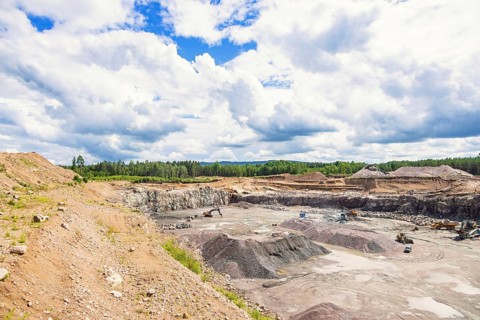 Active quarry with piles of gravel and machinery in a forest landscape in summer, Sweden, Europe