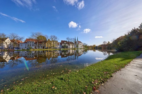 Riverbank of the Trave at high tide, blue sky with cumulus clouds, old town, Hanseatic city of