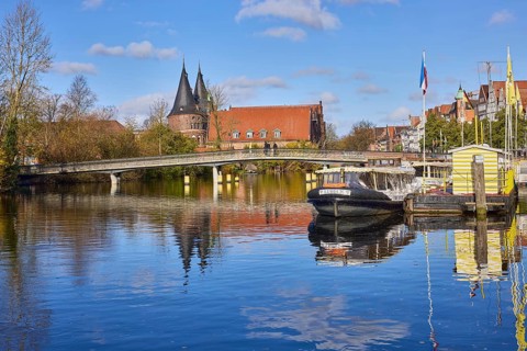 River Trave, pedestrian bridge Obertravebrücke, Holstentor, blue sky with fair weather clouds,