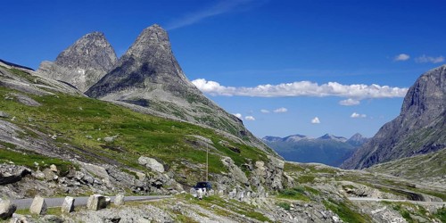 Two imposing mountain peaks rise into the blue sky, a road leads past, Trollstigen, Andalsnes,
