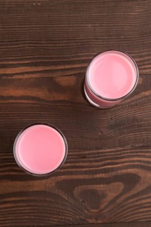 Sweet strawberry liqueur in glass on a brown wooden background. top view, close up, flat lay